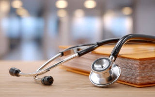 Ein Stethoskop liegt auf einem Lehrbuch (Foto: admin_design – stock.adobe.com)